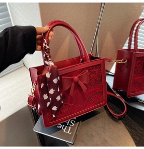 Close-up of red wedding handbag featuring 3D bow decoration and handle tied with silk scarf