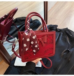 Detail of red bridal handbag featuring a large bow and silk scarf on the handle