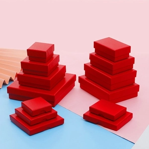 Multiple sizes of elegant red jewelry gift boxes stacked on a clean pastel background