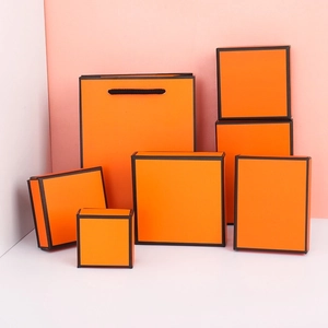 Set of luxury orange jewelry gift boxes and paper bag with elegant black border accents
