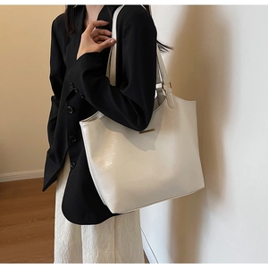 On-shoulder view of the white polished leather tote bag with minimalist metal buckle