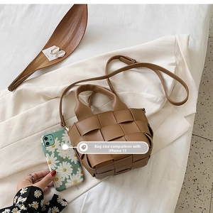 Detailed view of brown woven leather mini bucket bag next to an iPhone for size comparison
