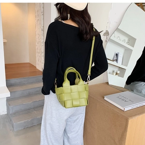 Detail view of the green woven leather mini bucket bag with a long shoulder strap