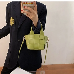Detailed texture of green woven leather mini tote bag with crossbody strap and handles
