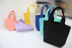 Selection of solid color canvas tote bags in various vibrant tones on a white surface