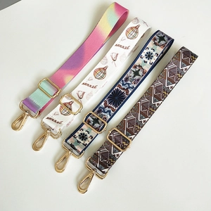 Detail of colorful canvas bag straps with floral patterns and gold metal buckles