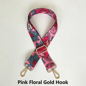 Detail of pink floral embroidery bag strap with gold lobster clasps and metal buckle