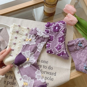 Detail of floral embroidery and textured patterns on mid-calf purple cotton socks