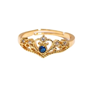 Golden crown ring featuring a blue gemstone and clear zircons with adjustable open band