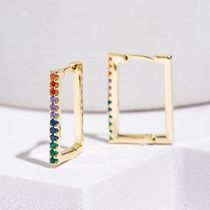 Close-up of golden rectangular hoop earrings with colorful zircon gemstones
