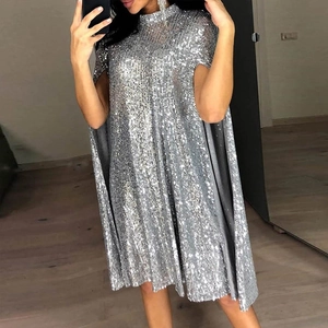 Detalle de vestido de lentejuelas plateadas con cuello alto y mangas de capa en selfie