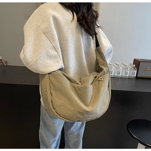 Khaki nylon dumpling crossbody bag with adjustable wide strap shown in a lifestyle setting
