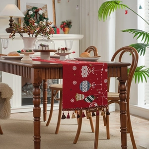 Green Christmas table runner with Santa jacquard and tassels on a wooden dining table