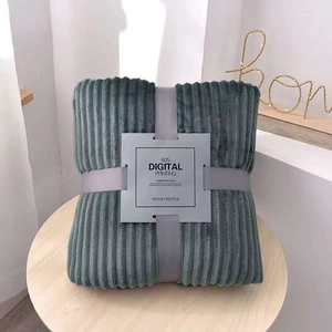 Detail of grey striped flannel blanket neatly folded with ribbon bow on wood table