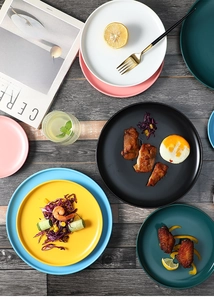 Flat lay of Nordic matte ceramic plates in various colors on a grey wooden background