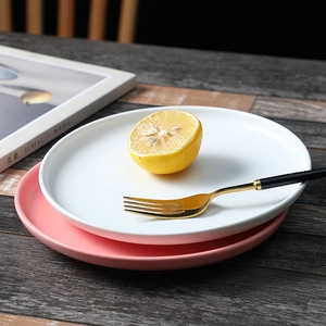 Nordic matte ceramic plates in white and pink stacked with lemon on a wooden table