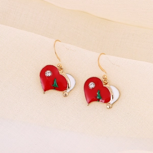 Macro shot of heart-shaped Christmas earrings with red enamel and a small green tree
