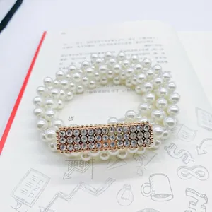 Detail of multi-layer pearl waist belt with rectangular gold buckle and inlaid rhinestones