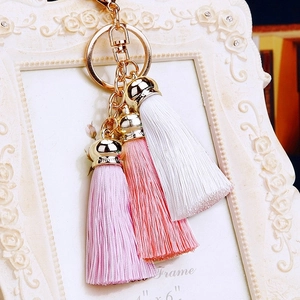 Detailed view of golden keychain with silk tassels in white, pink, and light purple