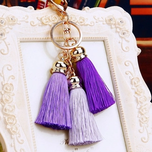 Detail of purple silk tassels with gold metal ring and clasp on decorative background