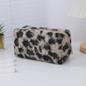 Close-up of leopard print plush makeup bag with silver zipper on a white desk