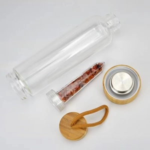 Bamboo lid crystal glass water bottle with energy stones and bamboo base on white background