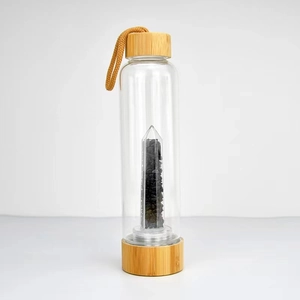 Detail of eco-friendly glass water bottle with bamboo lid and black crystal stones