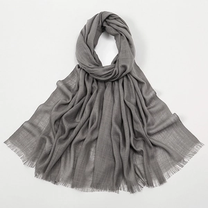 Macro shot of grey slub cotton scarf showing soft wrinkled texture and fine fringes
