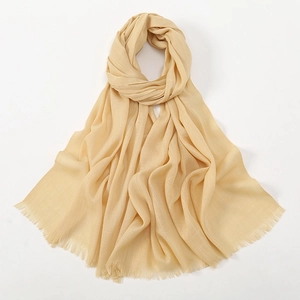 Close-up of beige breathable cotton scarf featuring elegant fringe and soft texture