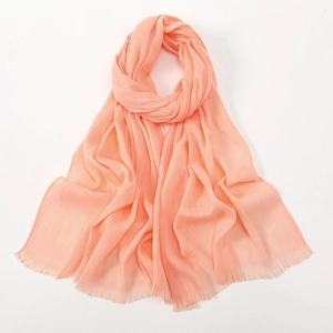 Detail of light orange bamboo cotton scarf showing soft texture and fringe tassels