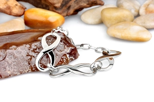 Macro shot of silver infinity symbol link bracelet on stones and wood background