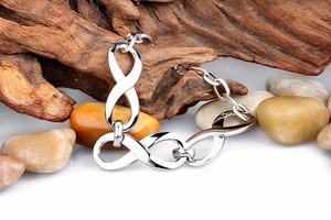 Detailed view of silver infinity chain bracelet displayed on natural wood and stones