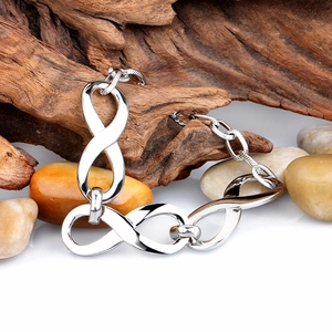 Minimalist silver infinity symbol chain bracelet displayed on rustic wood and pebbles