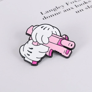 Close-up of pink enamel pistol pin with a cartoon white glove hand detail
