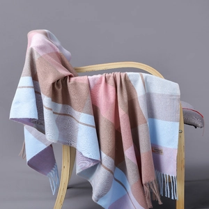Detailed close-up of colorful checkered cashmere scarf with fringes on a wooden chair