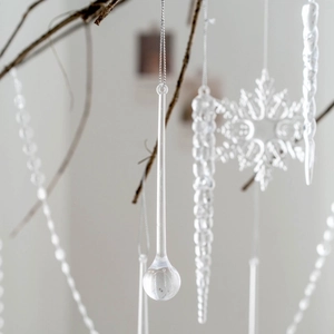 Transparent crystal icicle and snowflake Christmas tree ornaments on a winter branch