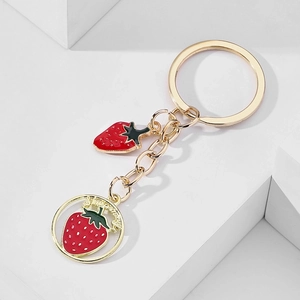 Creative strawberry fruit keychain with gold metal ring and red enamel charms on white