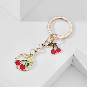 Creative gold metal keychain with red cherry charms on minimalist white background