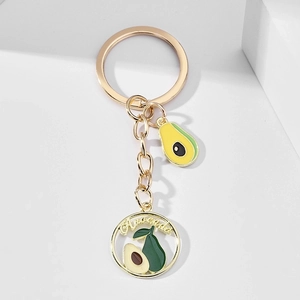 Detailed macro shot of gold-plated avocado keychain with green enamel and embossed text