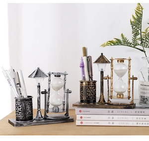 Vintage hourglass pen holder with street lamp in silver and bronze on a wooden desk