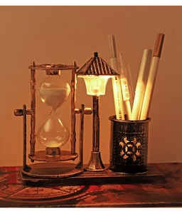 Macro view of vintage bronze hourglass and street lamp pencil holder with warm LED light