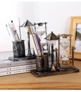 Detailed view of vintage metal hourglass and pen holder in bronze and silver finishes