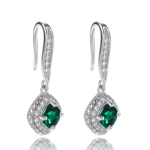 Macro shot of silver drop earrings featuring square green emerald-cut stones with halo crystals