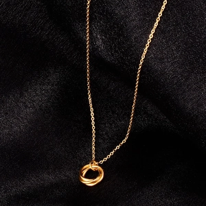 Minimalist 18K gold triple interlocking ring necklace on black silk background
