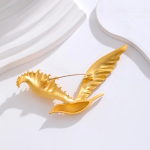 Vintage style gold-plated eagle brooch with textured wings on a minimalist white display