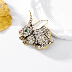 Gold rabbit brooch featuring sparkling diamonds and colorful enamel animal design