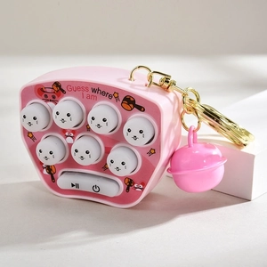 Pink mini whack-a-mole game keychain with bell and golden ring on white cubes