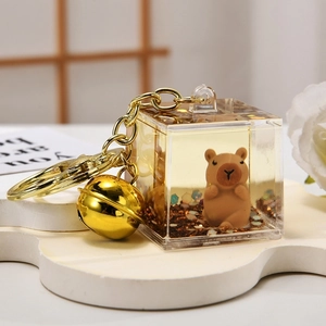 Capybara quicksand bottle keychain with gold bell and glitter in a transparent cube