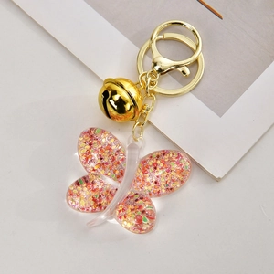 Detailed view of pink acrylic butterfly keychain with glitter, beads, and golden bell