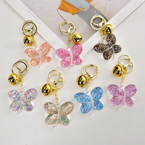 Set of colorful butterfly acrylic keychains with sequins and bells on a white background